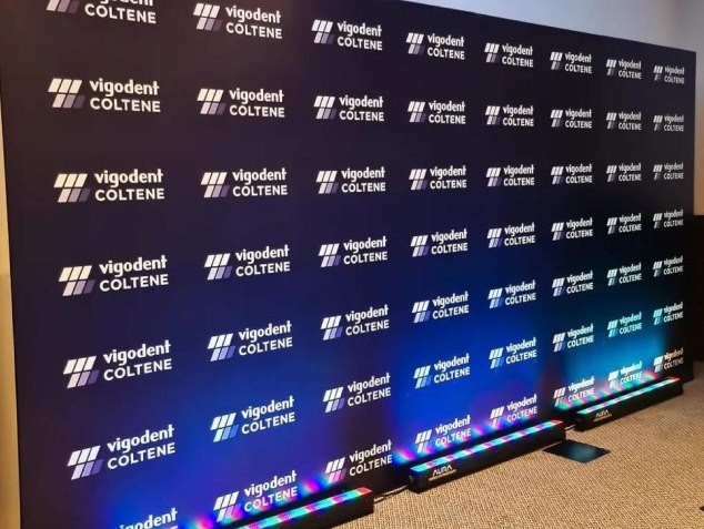 Backdrop impresso com a marca Vigodent Coltene, iluminado na base